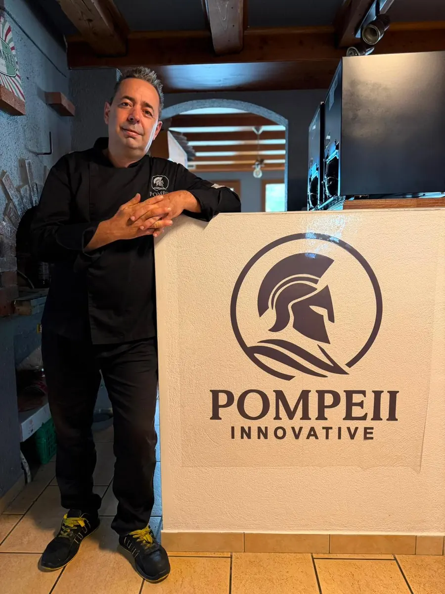 Armando, chef du restaurant Pompeii, devant le logo Pompeii Innovative dans la salle du restaurant